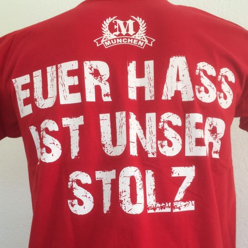 T-Shirt „Euer Hass ist unser Stolz“Rotes Kult T-Shirt „München –  Euer Hass ist unser Stolz“ mit zwei Motivseiten.Der Klassiker unter den München Fan-Shirts.Material: 100% Cotton/Baumwolle
