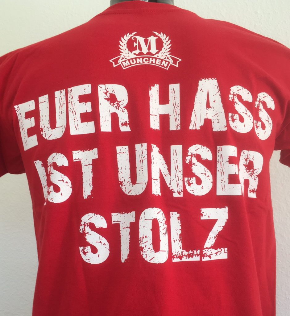 T-Shirt "Euer Hass ist unser Stolz"Rotes Kult T-Shirt "München -  Euer Hass ist unser Stolz" mit zwei Motivseiten.Der Klassiker unter den München Fan-Shirts.Material: 100% Cotton/BaumwolleDas T-Shirt "Euer Hass ist unser Stolz" war bisher nur an unserem Fanshop im U-Bahnhof Fröttmaning bei Heimspielen des FC Bayern München erhältlich. Ab jetzt gibt es diesen München Fanartikel für Euch auch in unserem Online-Shop. Wenn Ihr dieses T-Shirt bestellen solltet, haltet es (sowie auch Euere anderen roten Fansachen) immer in Ehren! Dieser Fanartikel ist mit viel Leidenschaft und Herzblut von unserem Fan-Point Team entworfen worden und hält von seiner Qualität her ewig. Einige von uns sind schon seit 1972 oder länger dabei, andere noch nicht so lange, oder manche erst relativ neu, aber alle sind rot bis unters Dach. Die ersten eigenen Fanartikel stellten wir  damals im Olympiastadion her und 1994 haben wir dann unseren ersten Verkaufsstand am Oly gehabt. Für uns gilt es also wirklich ”rot und weiss – ein Leben lang”. Wir versuchen ständig zusammen mit unseren Produzenten die Qualität und die Designs zu verbessern. Das herstellen von rot-weissen Fanartikeln für uns nicht einfach ein Beruf, "nein" es ist eine Berufung und unsere größte Freude ist, wenn sie Euch gefallen.Euer Fan Point Team.* München T-Shirt "Euer Hass ist unser Stolz"