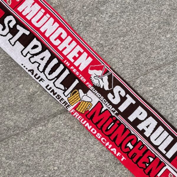 Material: 100% Polyacryl Größe: 140 x 16 cm Der gestrickte Schal "München - St Pauli AUF UNSERE FREUNDSCHAFT"  war bisher nur an unserem Fanshop im U-Bahnhof Fröttmaning bei Heimspielen des FC Bayern München erhältlich. Ab jetzt gibt es diesen Schal für Euch auch in unserem Online-Shop. Wenn Ihr diesen Schal bestellen solltet, haltet ihn (sowie auch Eure anderen roten Fanartikel) immer in Ehren! Dieser Schal ist mit viel Leidenschaft und Herzblut von unserem Fan-Point Team entworfen worden und hält von seiner Qualität her ewig. Einige von uns sind schon seit 1972 oder länger dabei, andere noch nicht so lange, oder manche erst relativ neu, aber alle sind rot bis unters Dach. Die ersten eigenen Fanartikel stellten wir damals im Olympiastadion her und 1994 haben wir dann unseren ersten Verkaufsstand am Oly gehabt. Für uns gilt es also wirklich “rot und weiss – ein Leben lang”. Wir versuchen ständig zusammen mit unseren Produzenten die Qualität und die Designs zu verbessern. Das herstellen von rot-weissen Fanartikeln für uns nicht einfach ein Beruf, “nein” es ist eine Berufung und unsere größte Freude ist, wenn sie Euch gefallen. #Schal "München - St Pauli AUF UNSERE FREUNDSCHAFT"